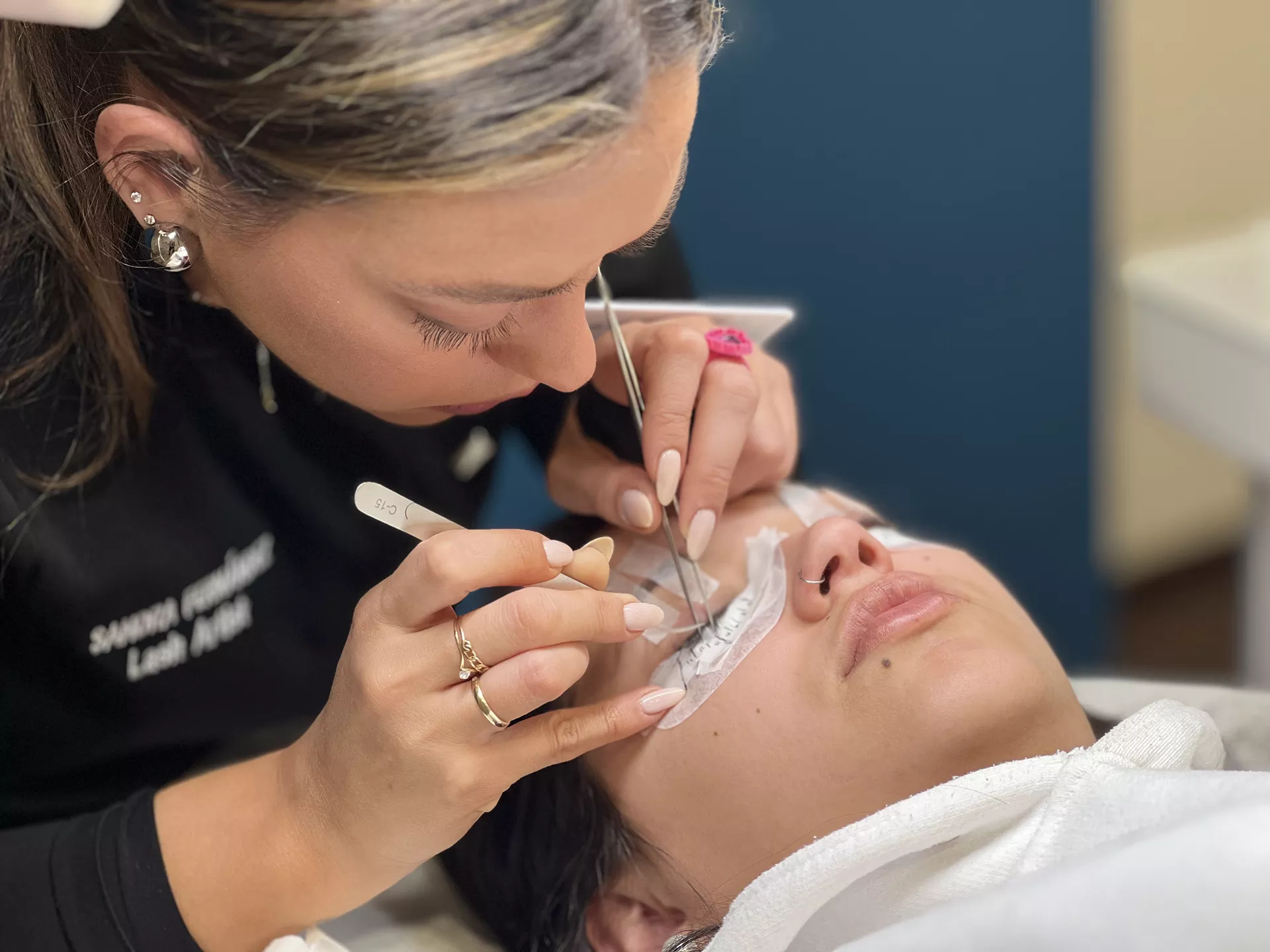 Mujer realizando tratamiento de pestañas a otra mujer